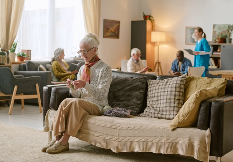 Senior Woman Knitting in a Lounge Area of an Assisted Living Facility Senior Woman Knitting in a Lounge Area of an Assisted Living Facility