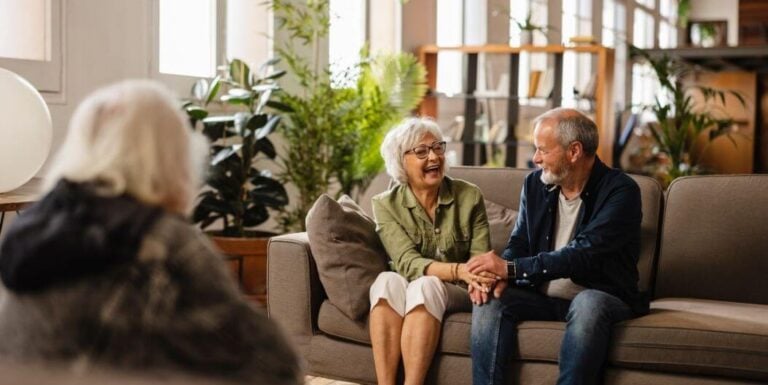 Elderly Couple Laughing Together in Memory Care Facility Lounge