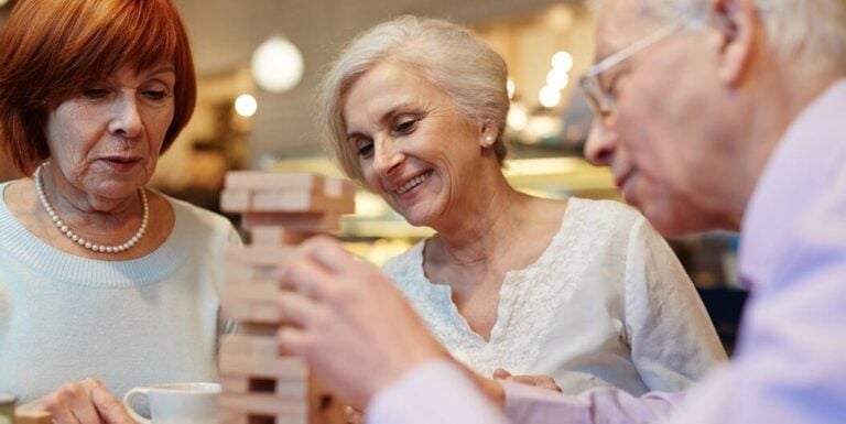Elderly Friends Playing Table Game and Laughing in Assisted Living Facility