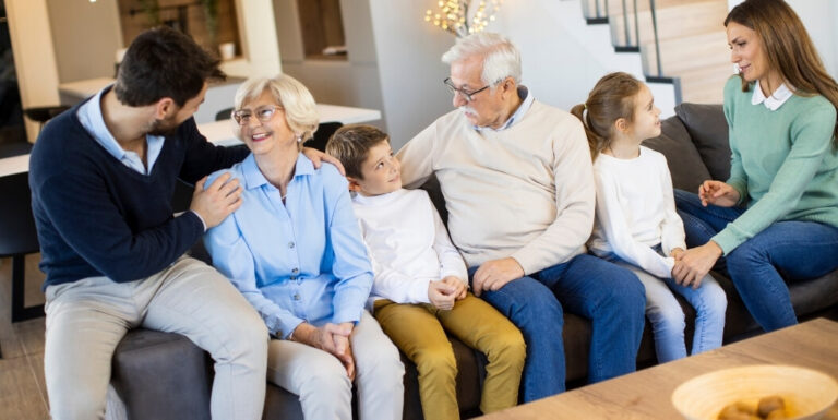Elderly Couple Sitting with Family Members and Grandchildren Indoors at an Assisted Living Facility